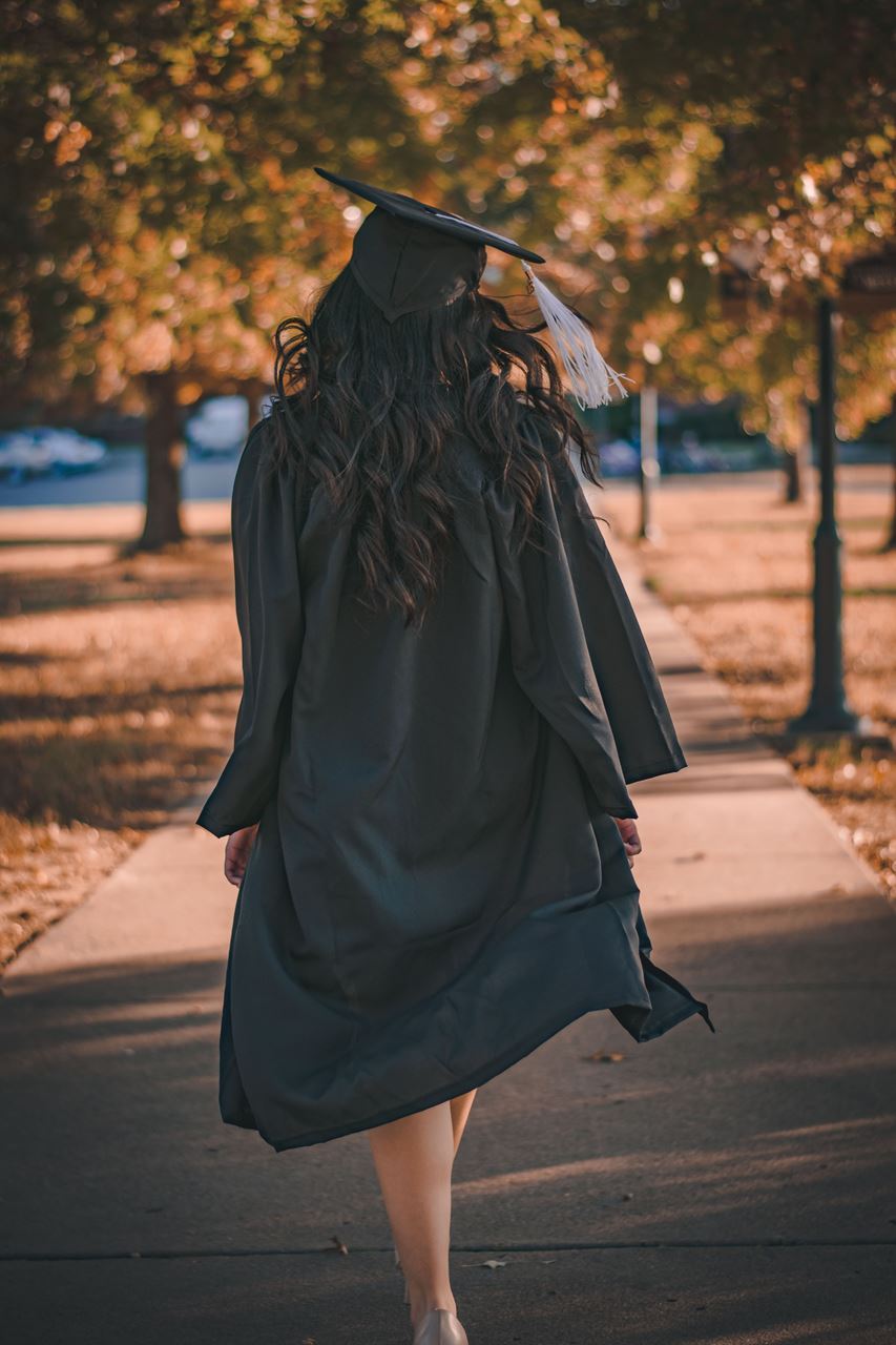 women in graduation gown walking away